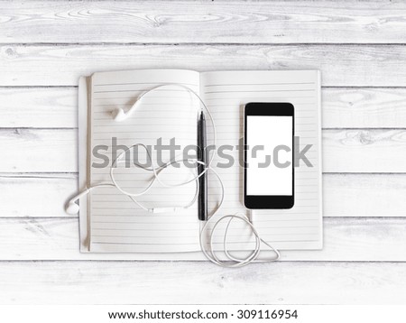Blank cell phone, notebook and headphones on a white wooden background