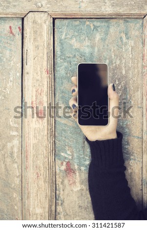 Girl holding cell phone and vintage wooden wall