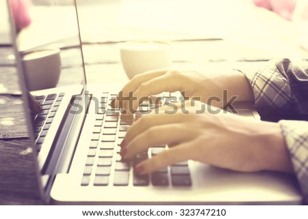 woman typing on a laptop through the rays of the sun, close up