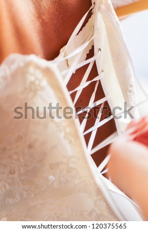 The bride\'s mother helps her to get dressed.