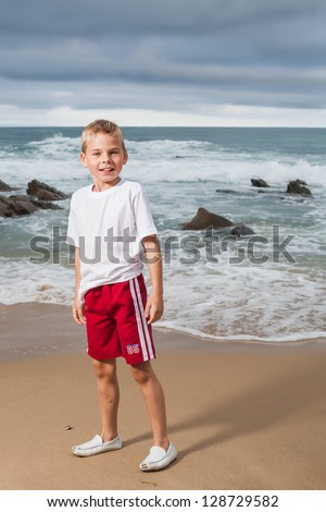 A blond little boy are being photographed on the beach.