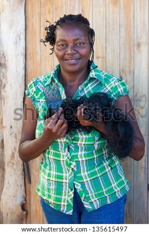 smiling african woman holding her weave in the transformation of a new hair style