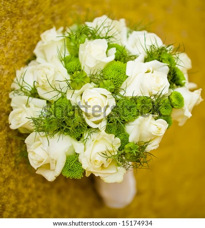 Wedding bouquet of white roses with lots of greenery lying on a carpet.