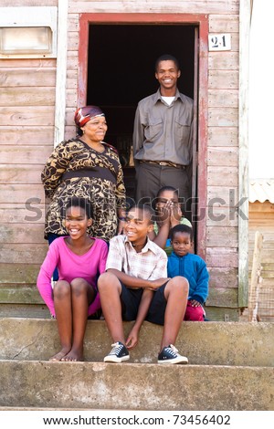 Cheerful black family on the steps infront of their rural house.