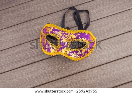Carnival mask in violet and gold on wooden background