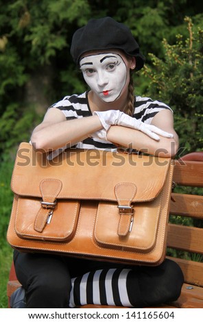 Portrait of mime in white gloves holding briefcase