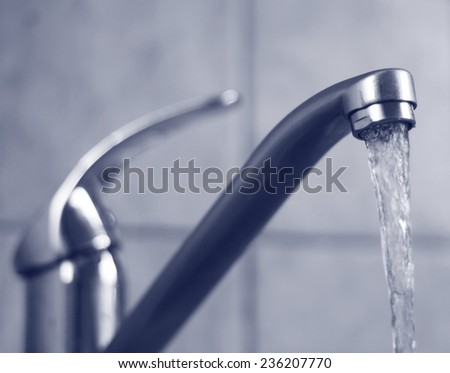 Water tap with flowing water. Selective focus, shallow depth of field.