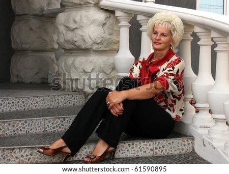 Women in bright blouse and dark trousers sitting on the stairs