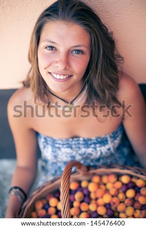 Beautiful young woman with basket of fruits - apricots and plums