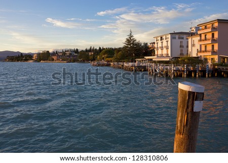 Sunset view of the jetty port and Sirmione waterfront on Lago di Garda, Italy. Warm light over the landscape at lake Garda.