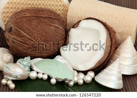 Coconut spa products with moisturiser, exfoliating scrubs, sea shells and pearls over bamboo background.