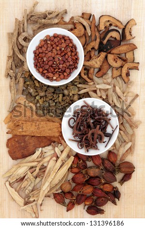 Chinese herbal medicine loose and in white porcelain bowls with chopsticks over papyrus background.