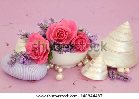 Lavender and rose flowers with natural soap, shells and pearls over mottled lilac background.