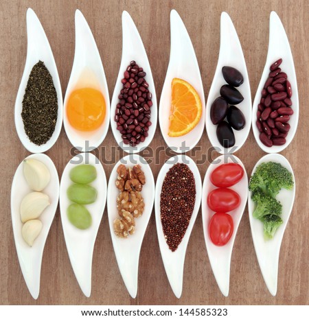 Healthy super food selection in white porcelain dishes over papyrus background.