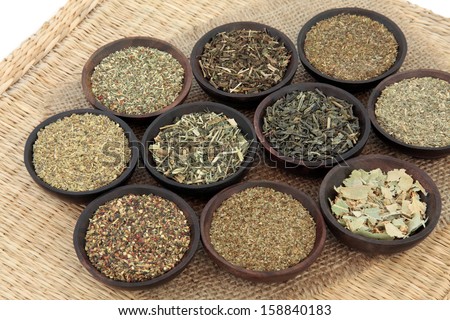 Green herb tea selection in wooden bowls over hessian and wicker background. Selective focus.