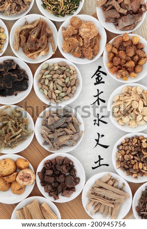Five elements chinese calligraphy script on rice paper with herbal medicine selection in white china bowls. Wu xing. Translation reads from top to bottom as, metal, wood, water, fire, earth.