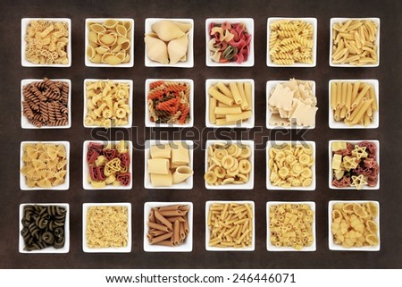 Large italian pasta dried food collection in square bowls over brown lokta paper background.