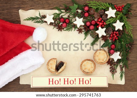 Christmas blank letter to santa claus with ho ho ho sign, hat, mince pies, gingerbread biscuits, holly, red baubles and winter greenery on parchment paper over oak background.