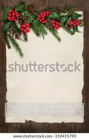 Christmas abstract background border with diamond ribbon, holly, ivy, cedar cypress and fir on parchment paper over old oak wood.