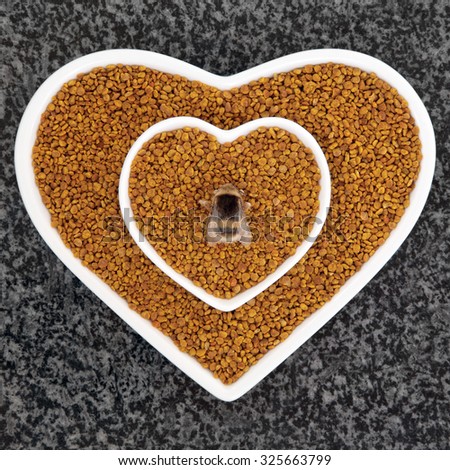 Bee pollen health food in heart shaped dishes with bumblebee over marble background.