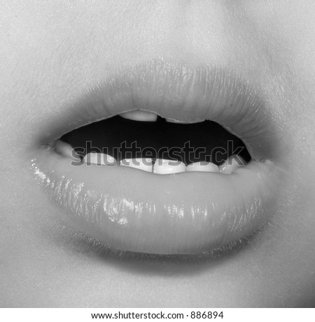 The open mouth of a little girl showing lips and teeth. In monochrome.