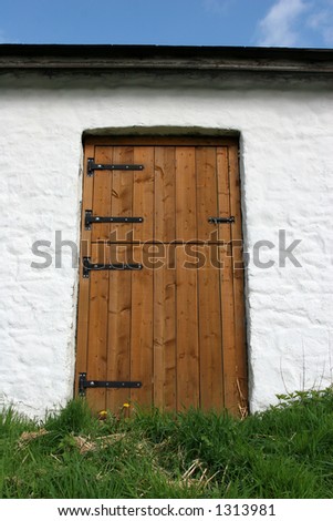 Wooden barn door on an old white lime washed barn.