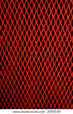 Red metal grill of diamond shaped mesh, against black.