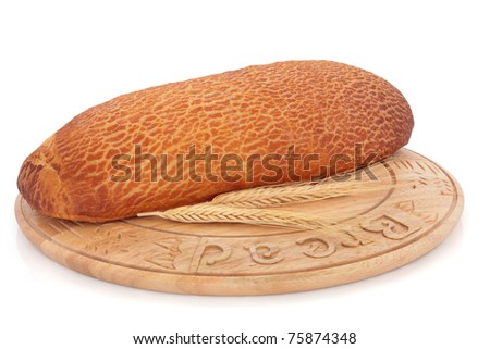 Tiger loaf with ears of wheat on a rustic wooden beech bread board, over white background. Mass produced bread board.