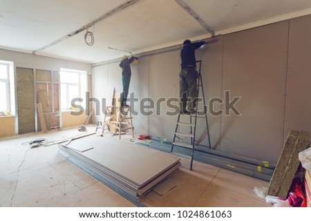 Workers are installing plasterboard (drywall) for gypsum walls in apartment is under construction, remodeling, renovation, extension, restoration and reconstruction. Foto stock © 