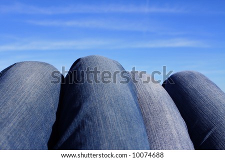 Four legs wearing jeans and looking like mountains against a blue sky
