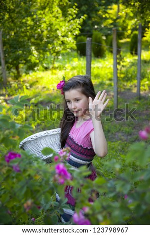 Sweet little girl picks oil aroma roses in the garden