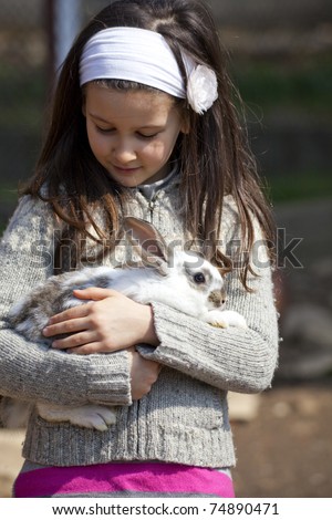 Sweet little girl in a farmyard with baby animals