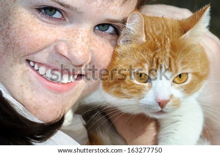 closeup portrait of happy freckled teenage girl and cat