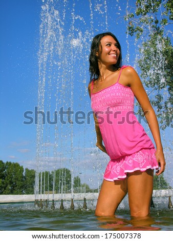 young attractive woman cooling in the fountain in hot weather