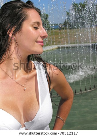beautiful woman in white dress, cooling near the fountain in hot day