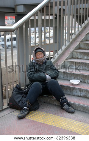 BEIJING, CHINA - MARCH 06: Unidentified old Chinese woman begs for money at the Train Station March 7, 2010 in Beijing, China. Shelter is hard to find for the poor even during the winter.