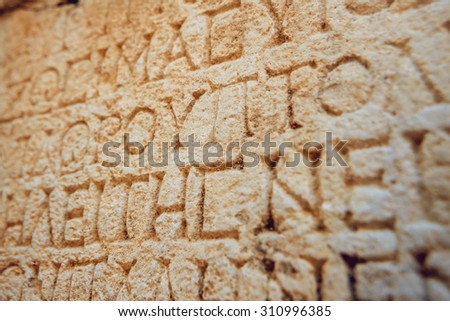 Ancient letters carved on a stone wall. Background