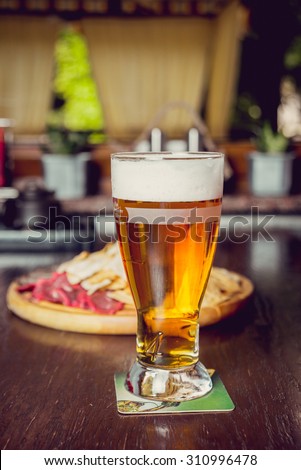 Meat and chips on a wooden plate with beer. Restaurant