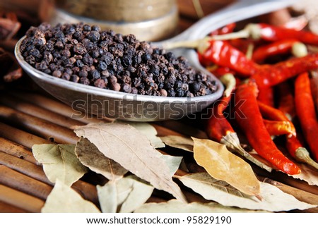 Black pepper in a spoon. Red pepper pods