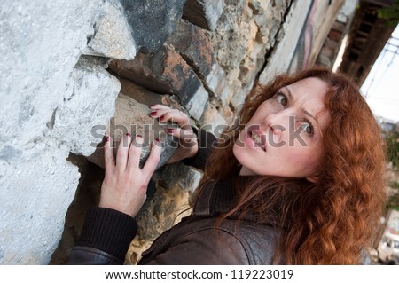 woman in the leather jacket trying to hide something in the wall