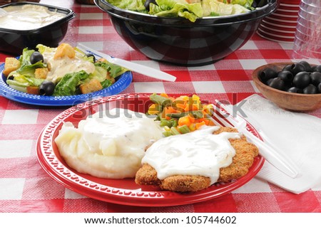 A picnic table with country fried steak and salad