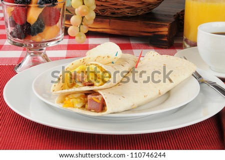 Ham, egg and cheese breakfast burrito with a bowl of fruit