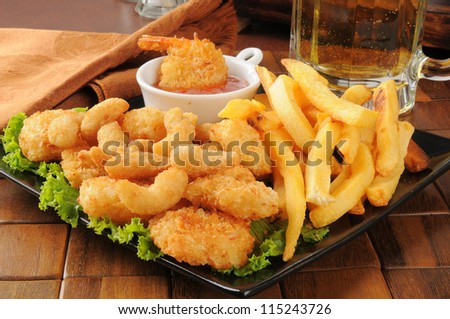 A snack platter with popcorn and coconut shrimp, fries and beer