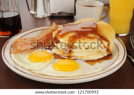 A bacon and egg breakfast with pancakes and orange juice