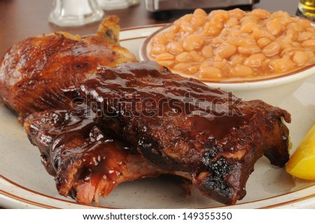 Closeup of barbecued ribs and chicken with baked beans
