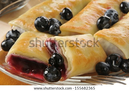 Closeup of golden blueberry blintzes or crepes with fresh berries
