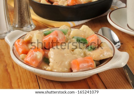 A bowl of chicken and dumplings served from a cast iron skillet