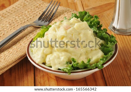 A small bowl of mustard potato salad on a rustic wooden table