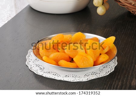 Dried peaches in a silver serving dish near a basket of fruit