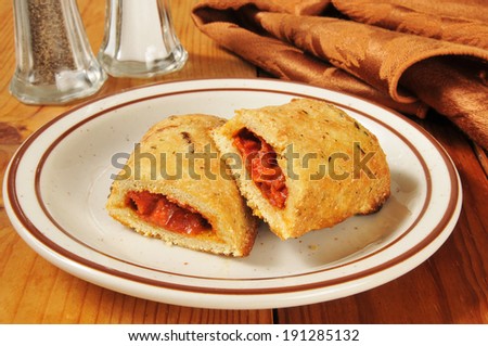 a plate of pizza rolls, or calzones on a rustic wooden table